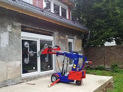 Vor einem Haus steht eine blau-rote Maschine.